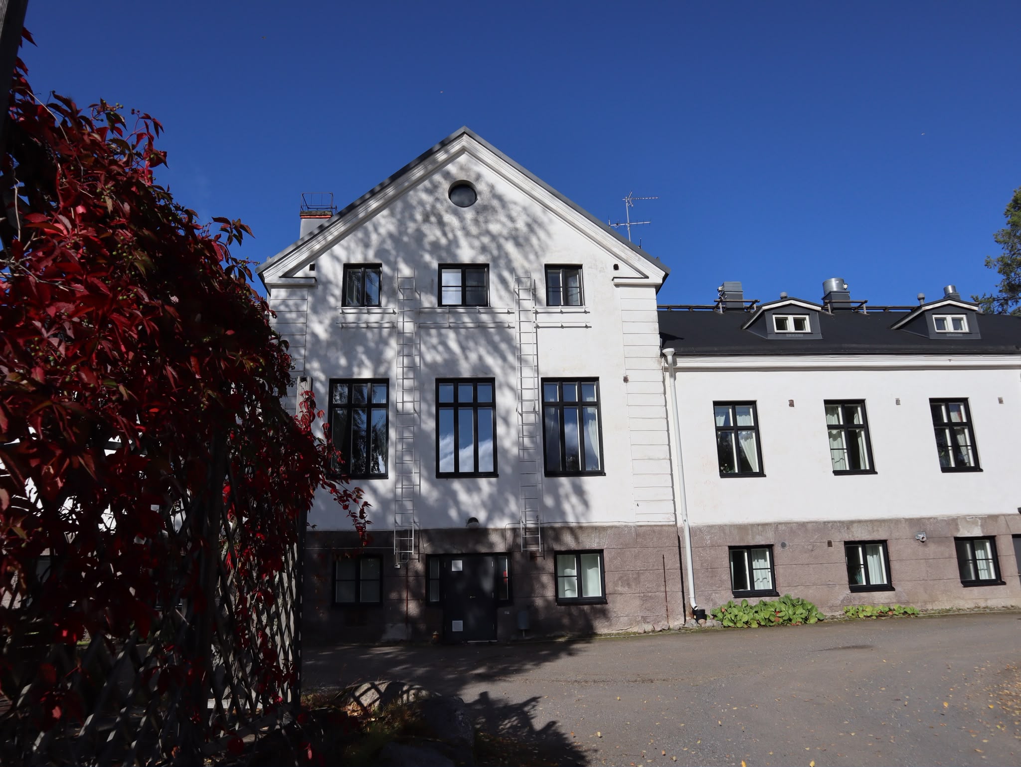 Satulinnan vaalea päärakennus ja syksynpunainen köynnös